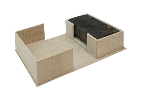 Beige Klappkassette geöffnet mit einem historischen dunkelbraunem Buch.